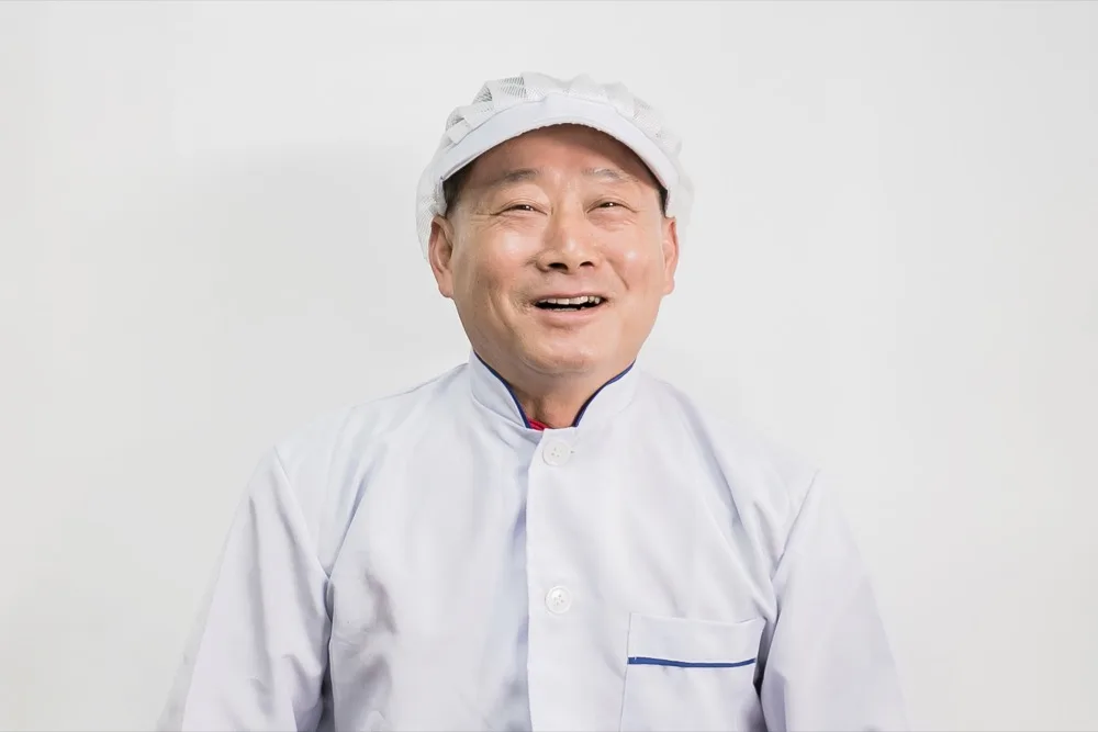 흰 조리복과 위생모를 쓰고 웃고 있는 대왕수육 사장님